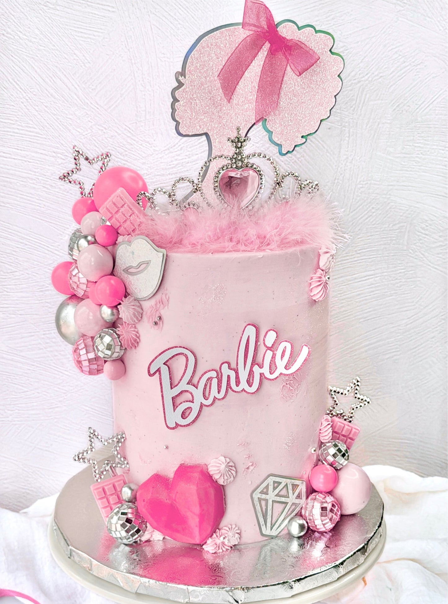 Barbie-themed cake with pink decorations and tiara on a white background
