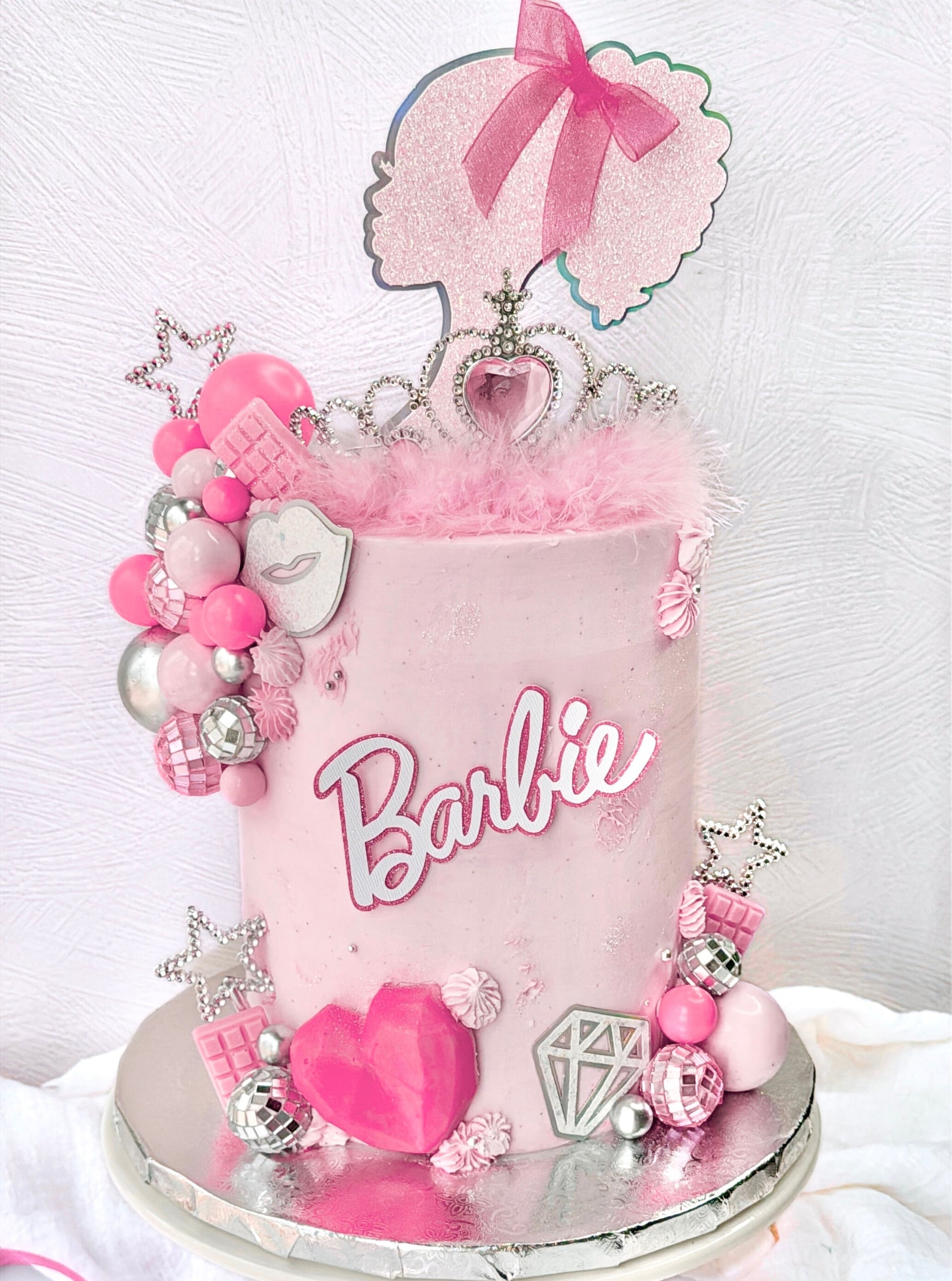 Barbie-themed cake with pink decorations and tiara on a white background